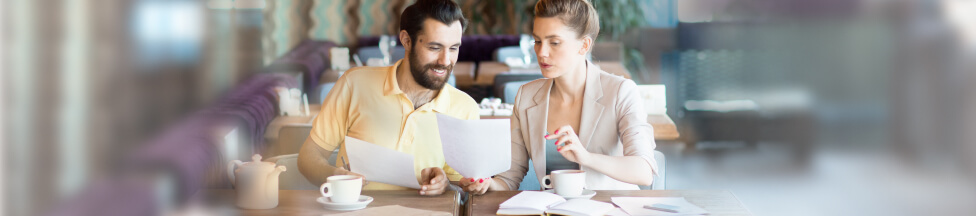 Man and woman review documents in cafeteria