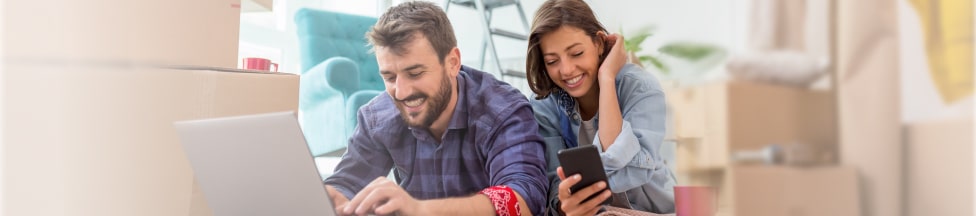 Happy couple working at home with computer and mobile phone.