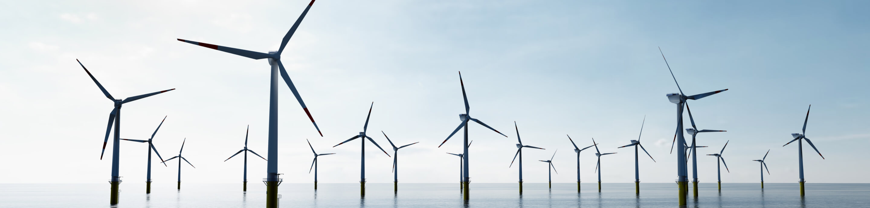 Offshore wind farm with wind turbines in the water under a clear sky.